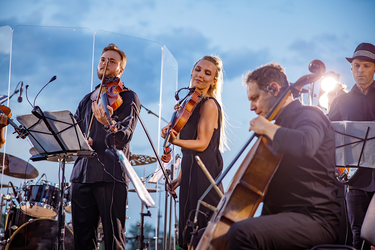 Professional musicians playing violin violoncello while giving live concert street